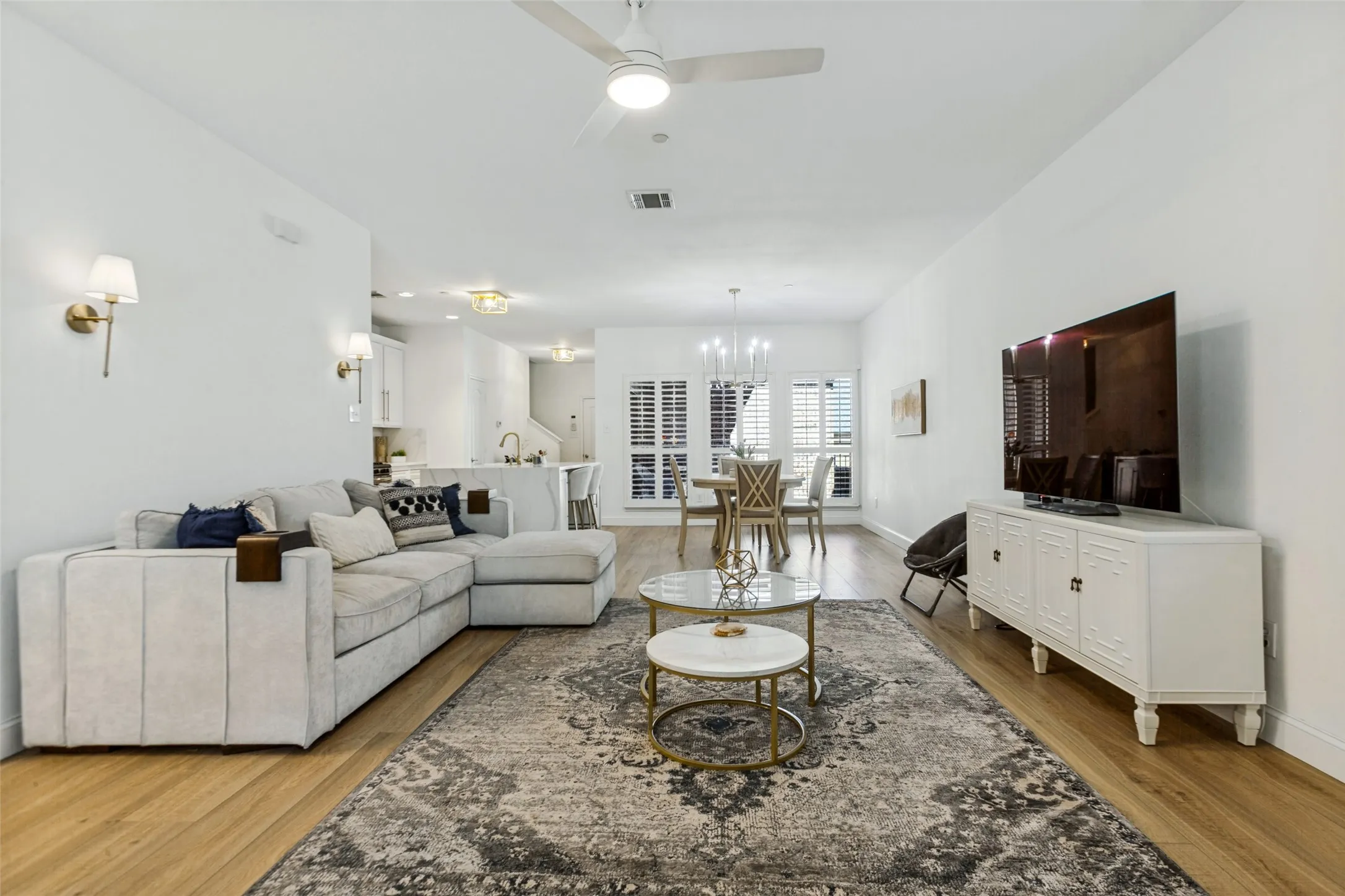 Open-concept living area featuring LVP flooring, recessed lighting, and white plantation shutters