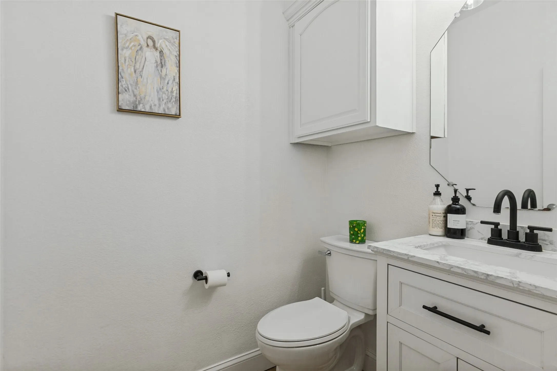 White shaker-style vanity with dark hardware, undermount sink, and stone-finish countertop Large private half bath downstairs