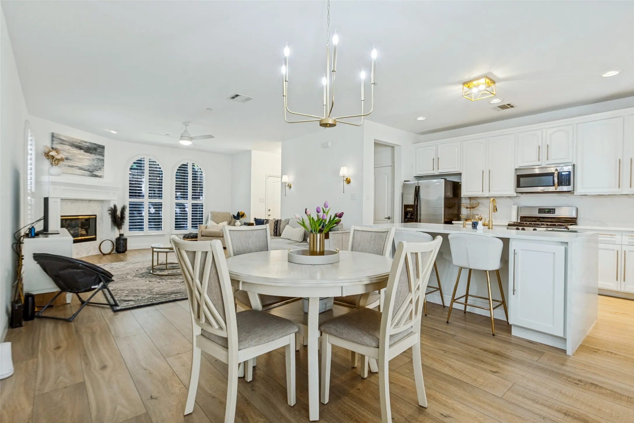 Open-concept living space with wood-finish flooring, a white kitchen island, and stainless steel appliances