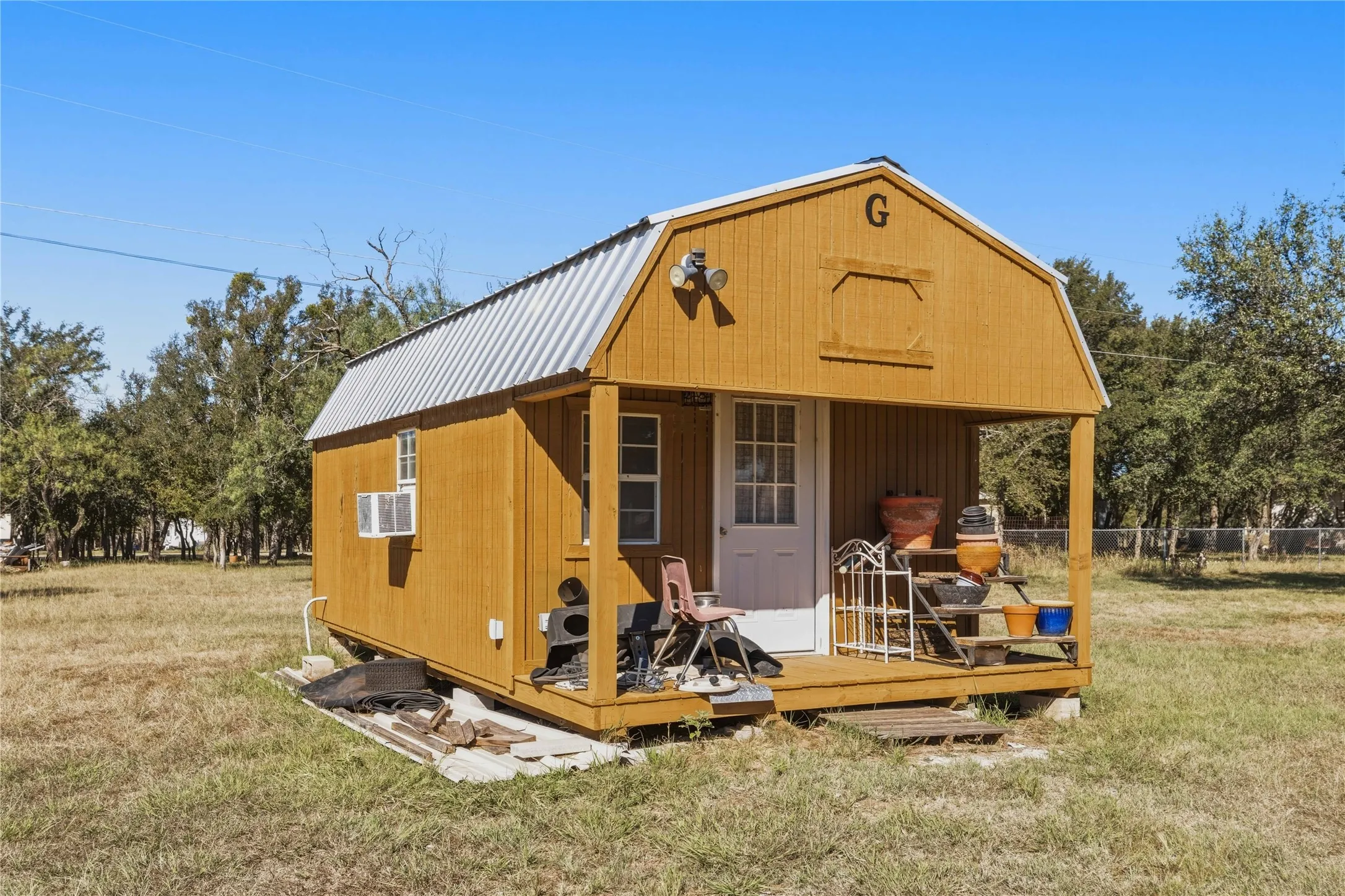 Light brown siding exterior with a gambrel roof and front porch