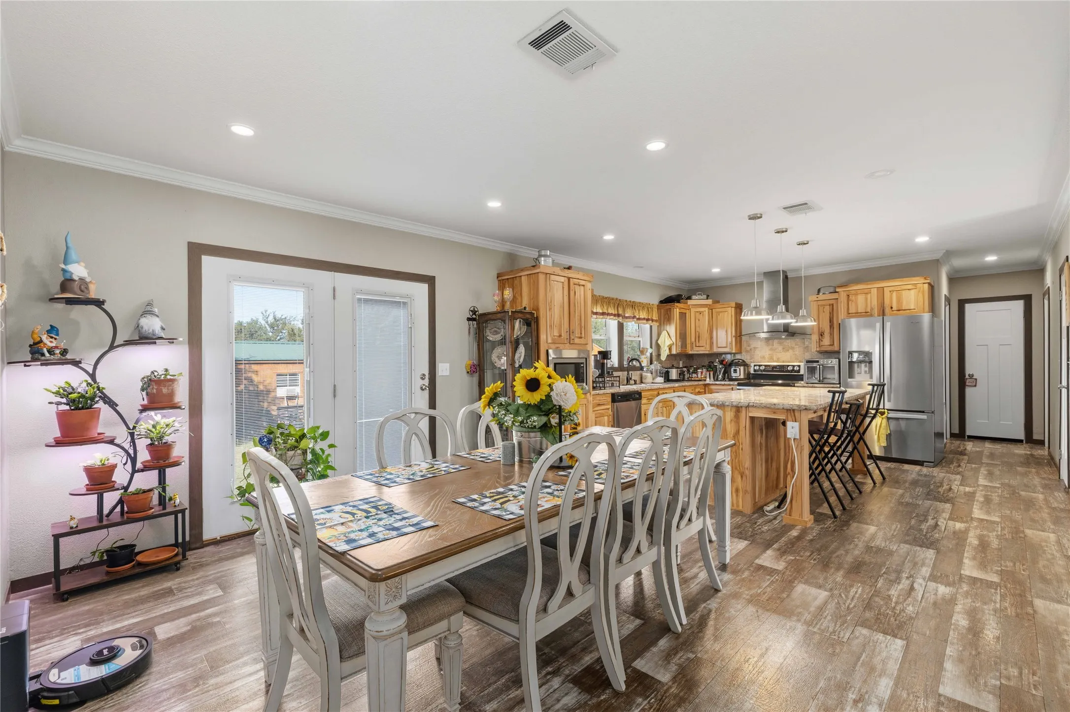 Open-concept dining and kitchen space featuring wood-finish flooring, recessed lighting, and crown molding
