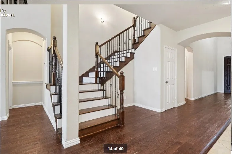 Wood-finish flooring throughout, featuring a staircase with wood treads and wrought iron balusters