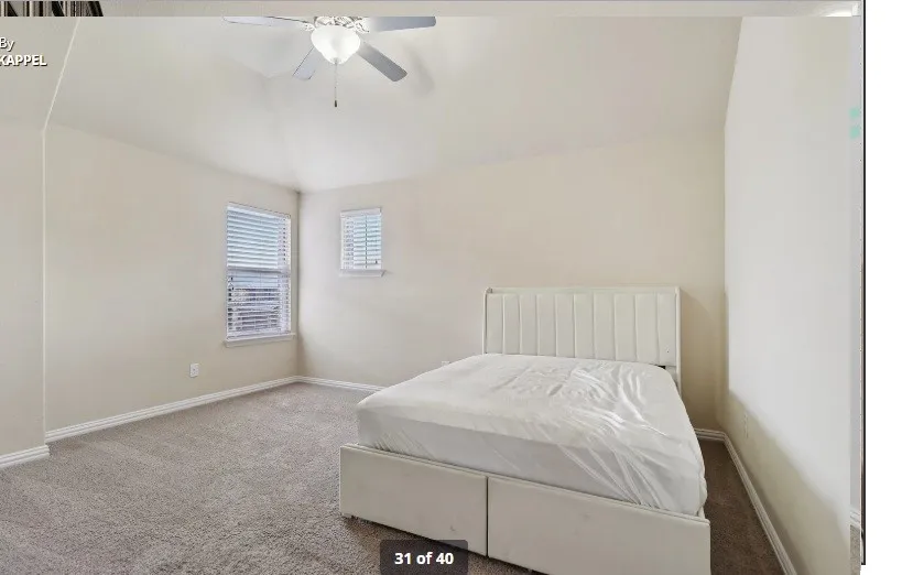 Vaulted ceiling with a ceiling fan, carpeted flooring, and two windows with blinds