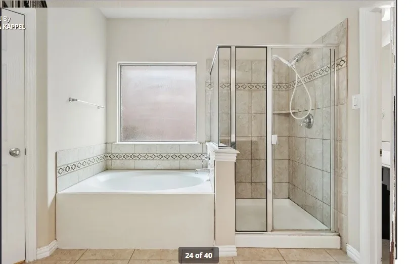 Soaking tub with tiled surround, separate glass-enclosed shower, patterned tile accent bands, and frosted window