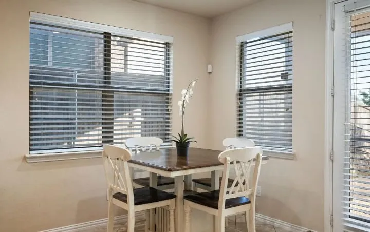 White-framed windows with horizontal blinds, neutral wall paint, and tiled flooring