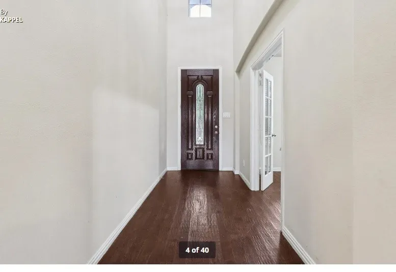 Double-height foyer featuring wood-finish flooring, a dark wood entry door with decorative glass, and a transom window