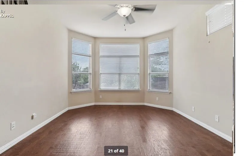 Bay window with multiple windows, wood-finish flooring, ceiling fan, and neutral wall tones