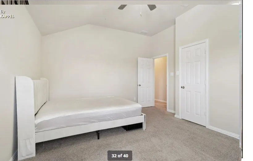 Vaulted ceiling, ceiling fan, neutral carpet flooring, white paneled doors, and light-toned walls