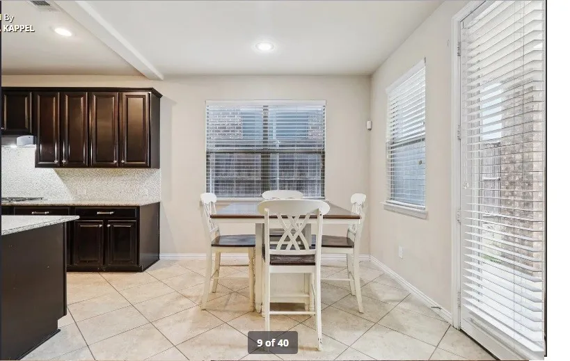 Dark wood-finish cabinetry, light-toned tile flooring, recessed lighting, and a window with blinds