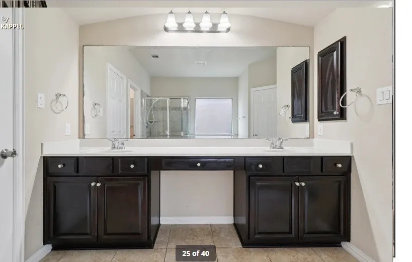 Double vanity with dark wood-finish cabinetry, integrated sinks, and a large wall-mounted mirror