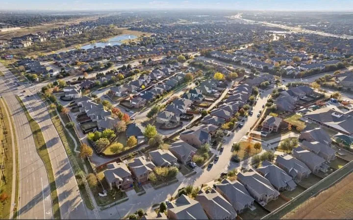 Mature residential neighborhood featuring diverse architectural styles, paved roadways, and a prominent nearby lake