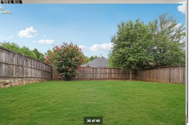 Expansive grassy yard with wood fencing and a stone retaining wall