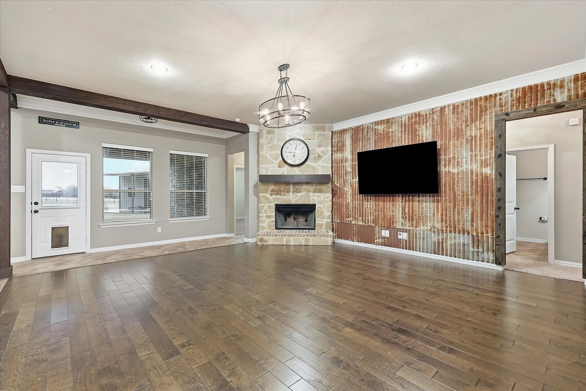 Hardwood-style flooring, corner stone fireplace with wood mantel, corrugated metal accent wall, exposed ceiling beam, and recessed lighting