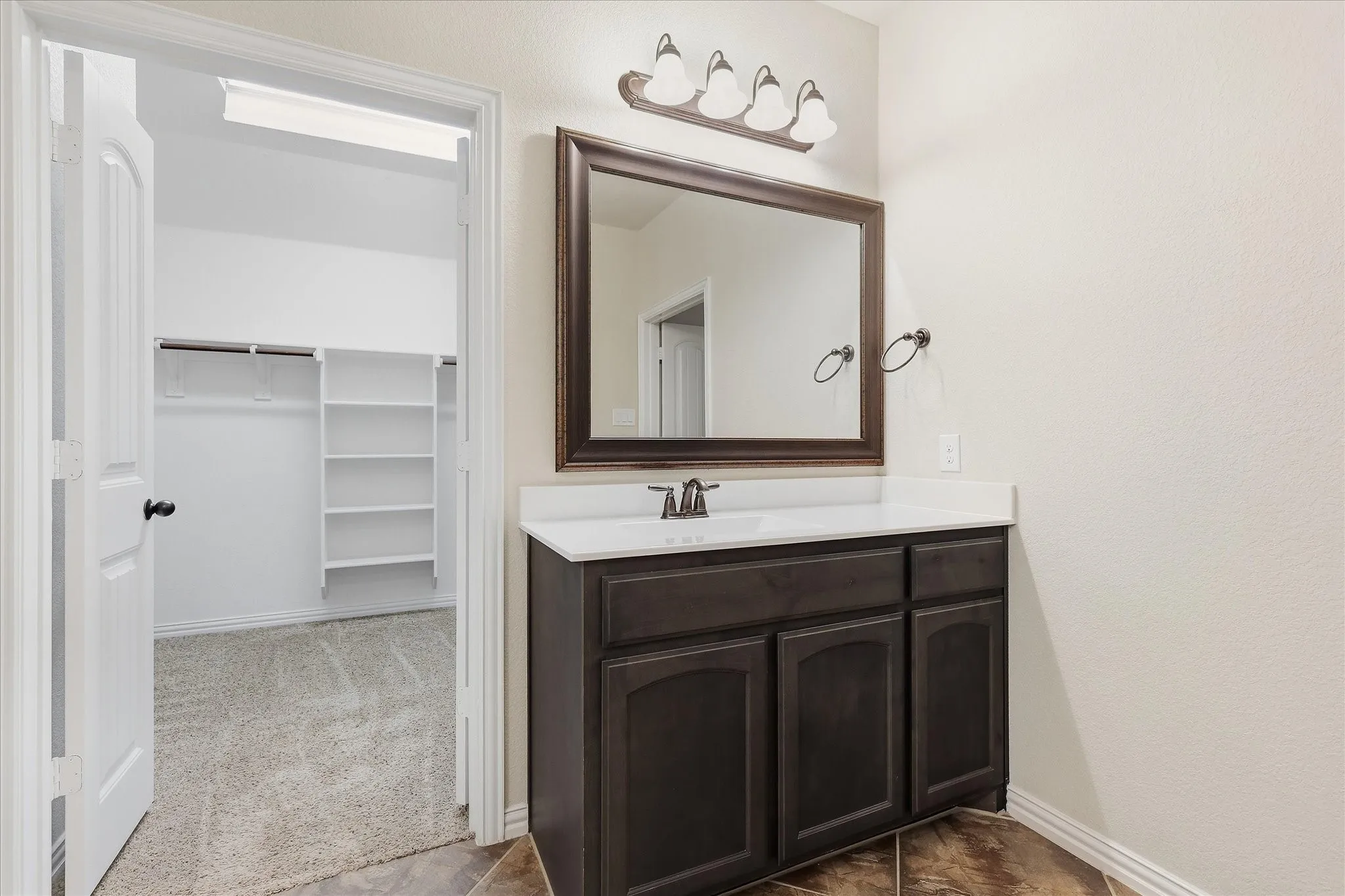 Vanity with dark wood cabinetry, white countertop, and integrated sink