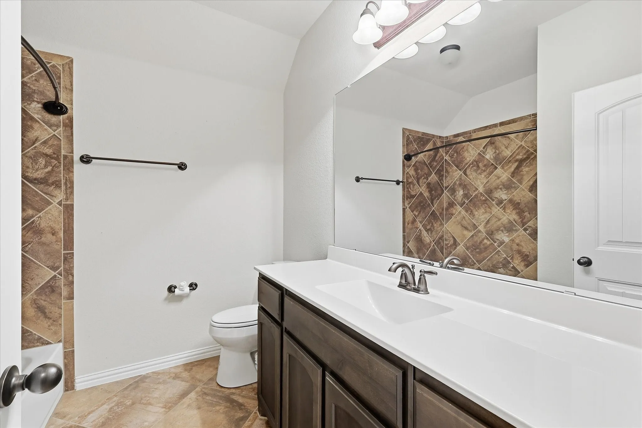 Brown tile shower surround with dark bronze fixtures