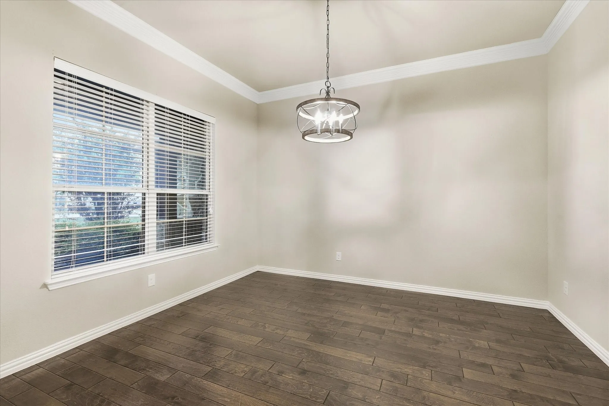 Wood-finish flooring, crown molding, and a decorative chandelier