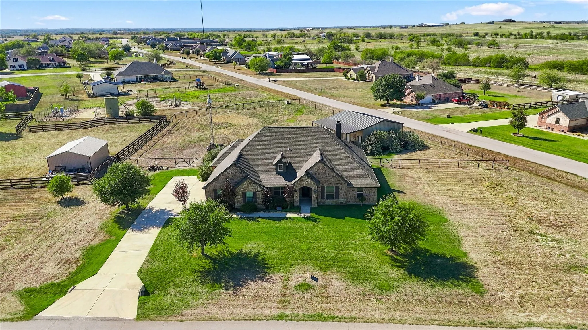 Brick and stone exterior residence with a gabled roof, established landscaping, and an extended concrete driveway