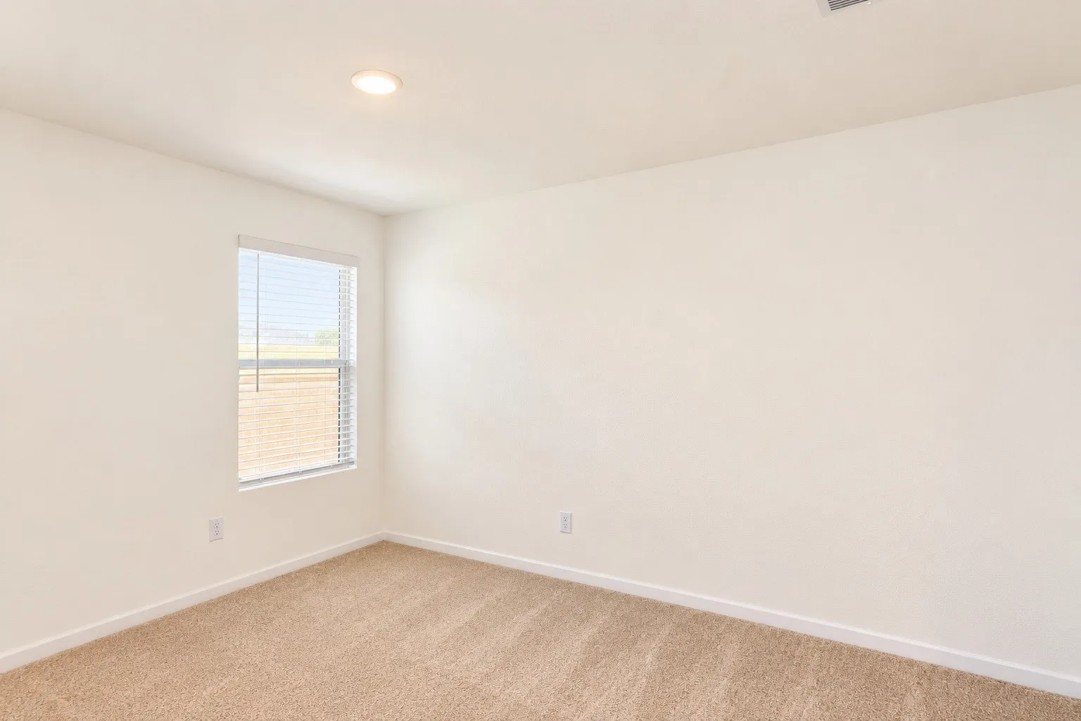Recessed ceiling lighting, neutral carpet, white walls, and a window with blinds