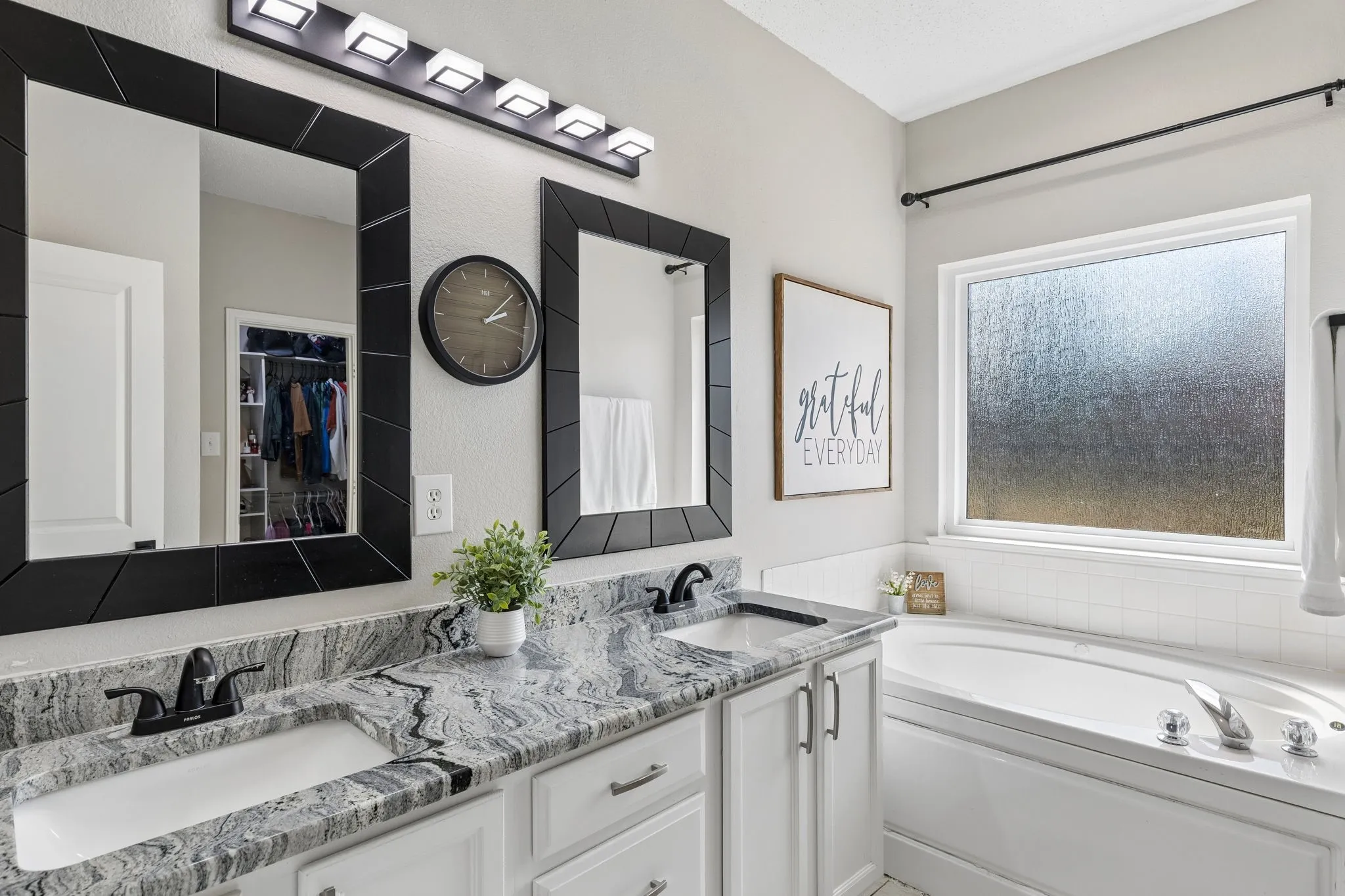Dual vanity with undermount sinks, patterned stone countertop, and matte black fixtures