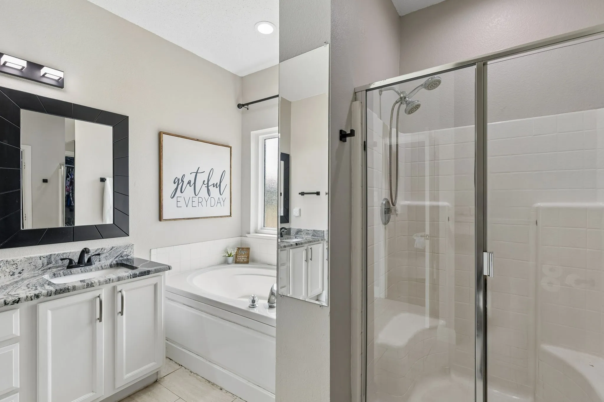 Dual vanity featuring white cabinetry and stone countertops