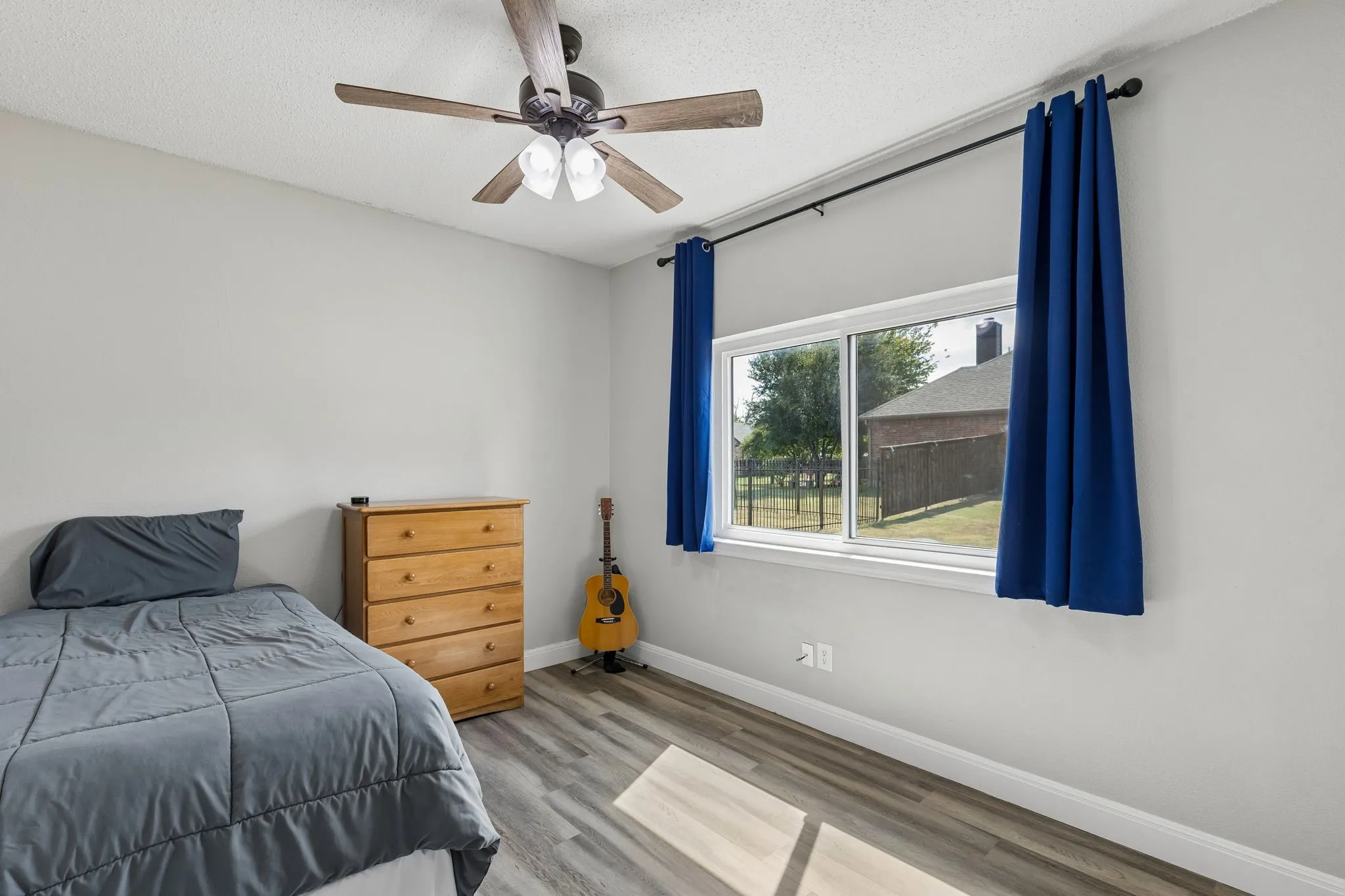 Wood-finish flooring, ceiling fan with integrated lighting, white trim, and a window for natural light