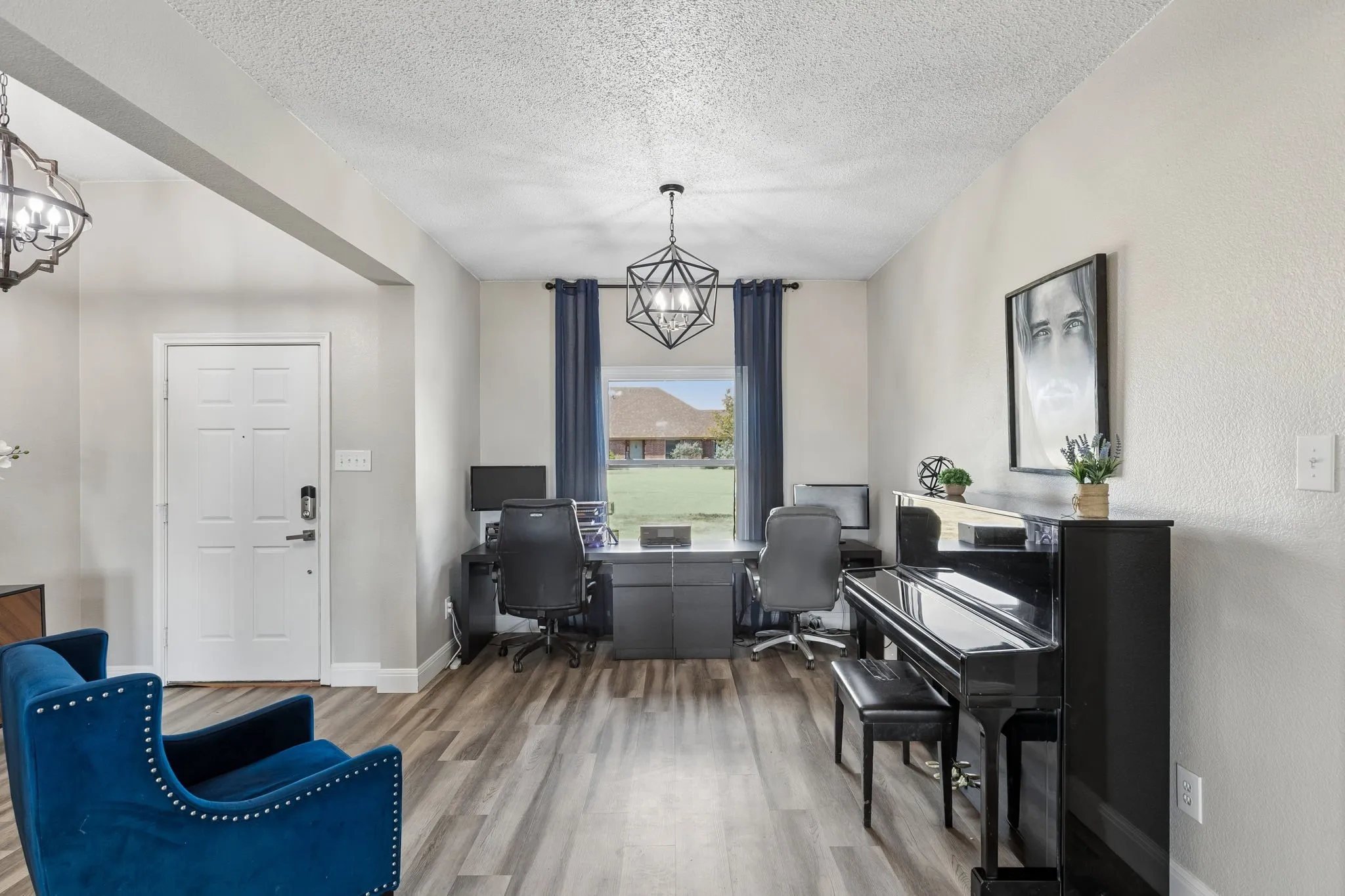 Wood-finish flooring, recessed lighting, and a contemporary chandelier illuminate this versatile interior space