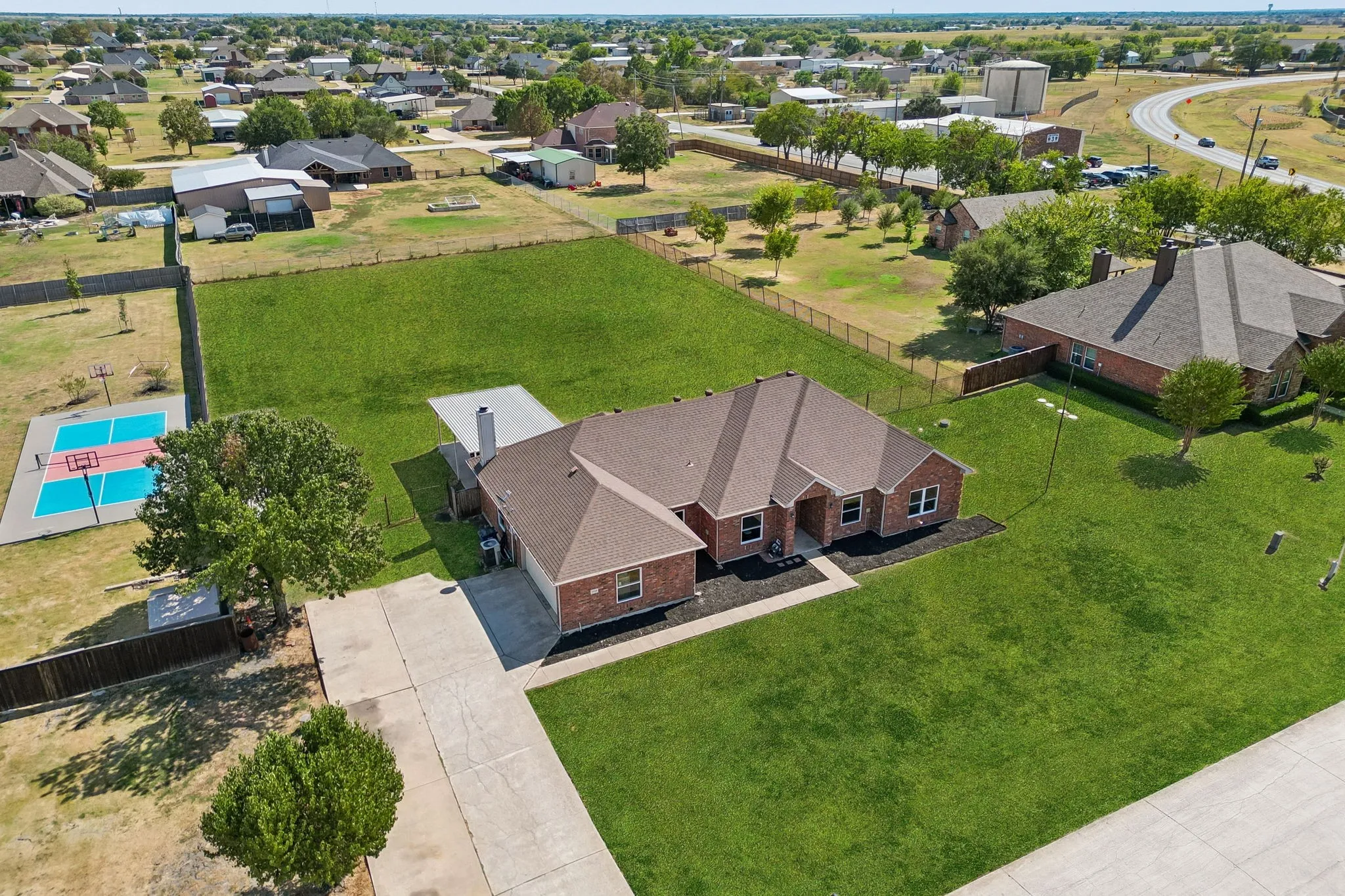Brick exterior residence with a concrete driveway, attached garage, and a covered patio