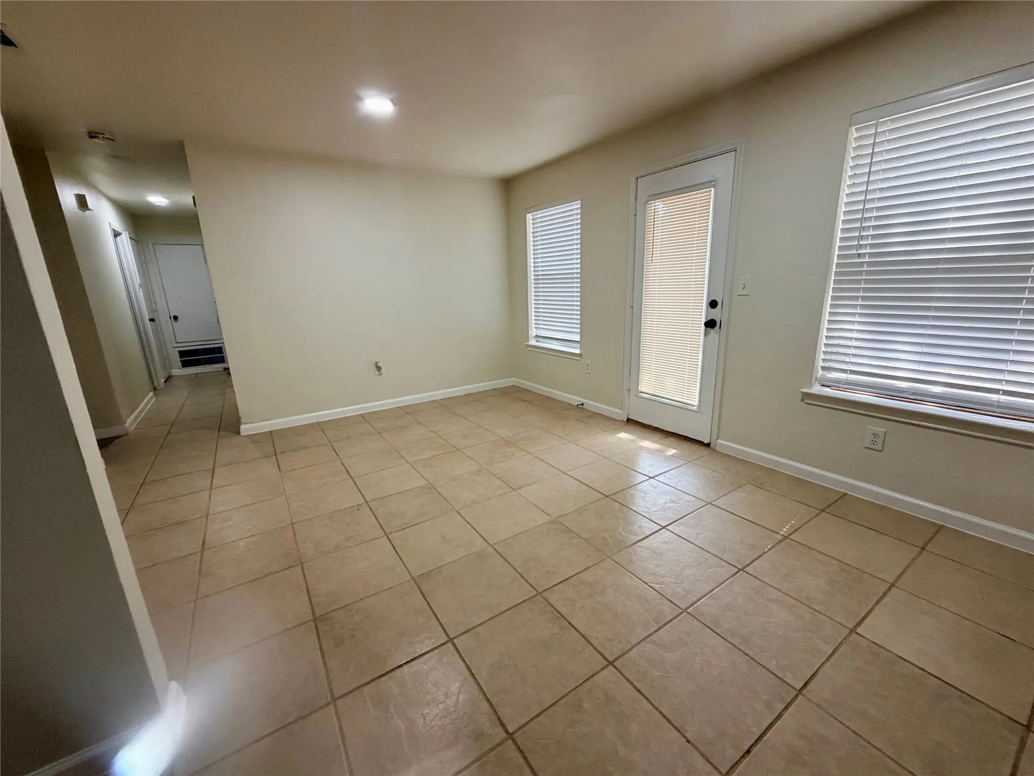 Ceramic tile flooring throughout, featuring a glass-paneled exterior door and two windows with horizontal blinds