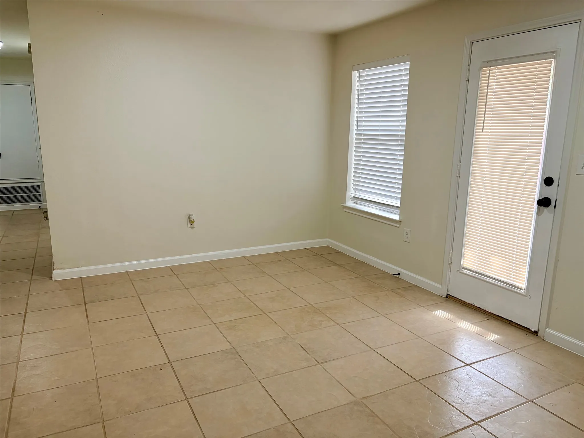 Tile flooring throughout, neutral wall paint, white trim, and a white door with integrated blinds