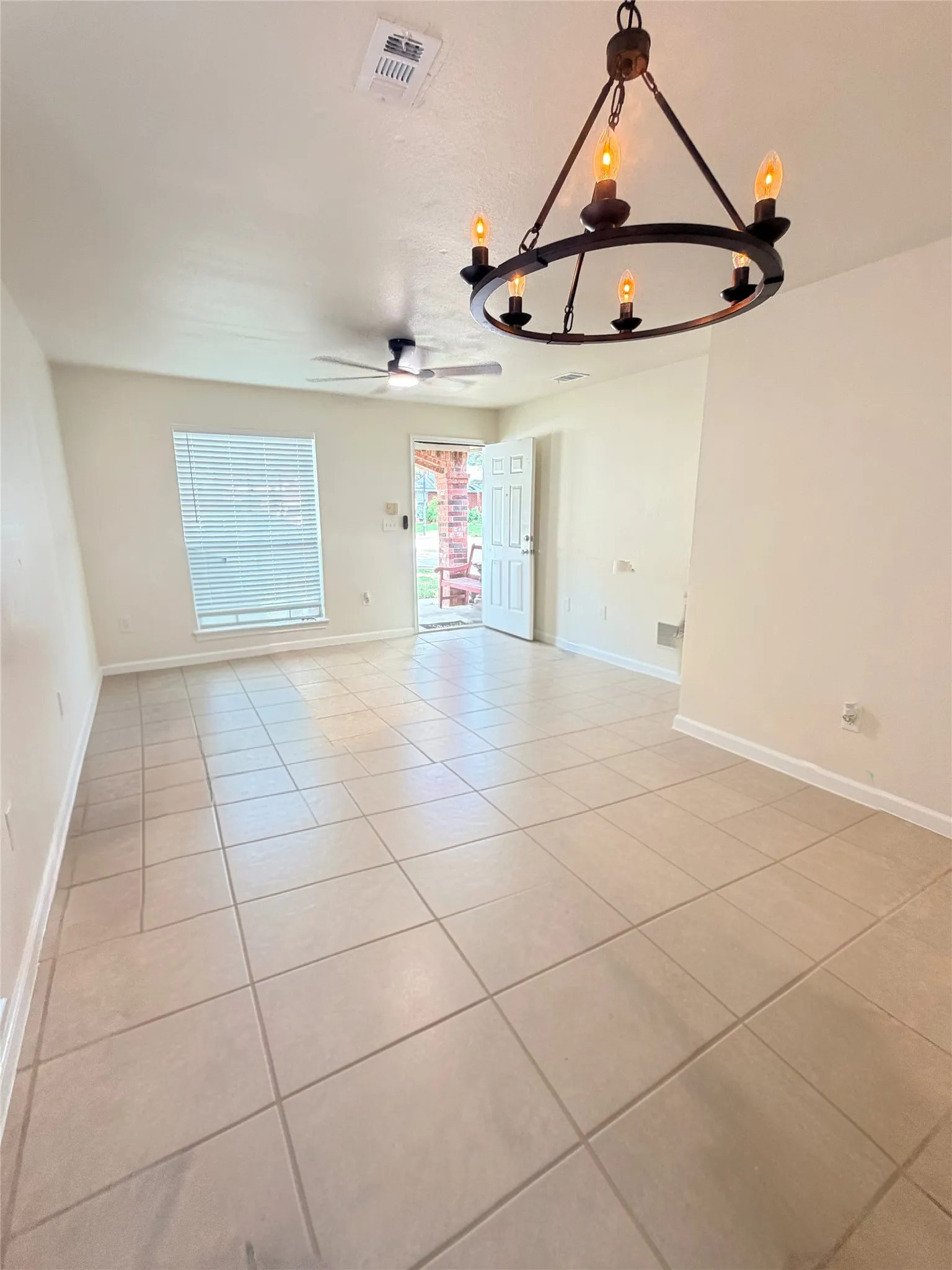 Tile flooring, ceiling fan, window blinds, and a decorative chandelier