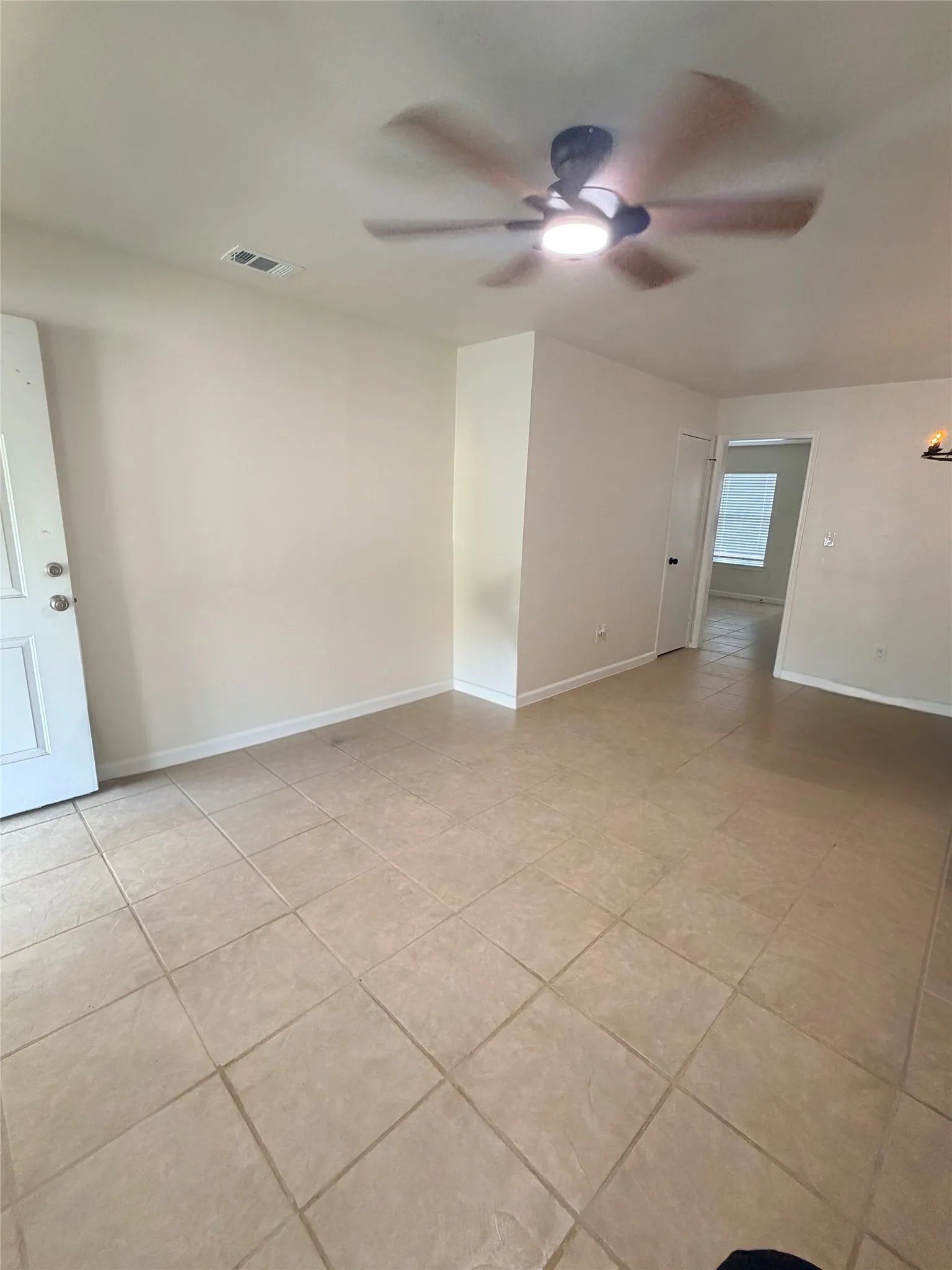 Ceiling fan with integrated lighting, tile flooring, and neutral wall tones