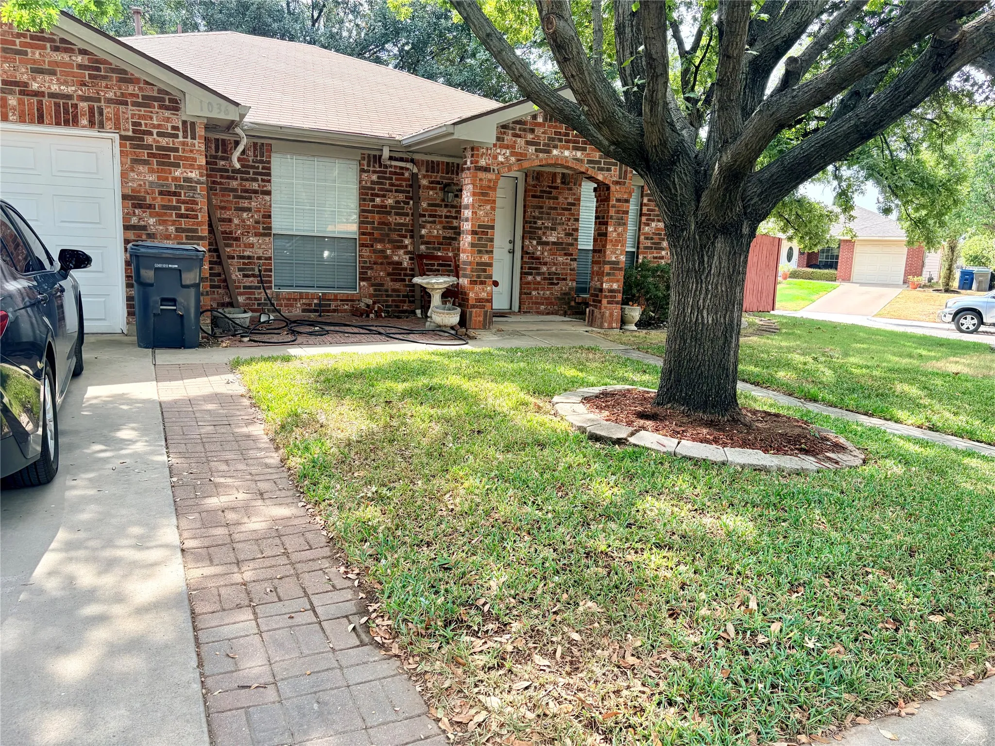 Brick exterior with an arched entryway, attached garage, and a concrete driveway