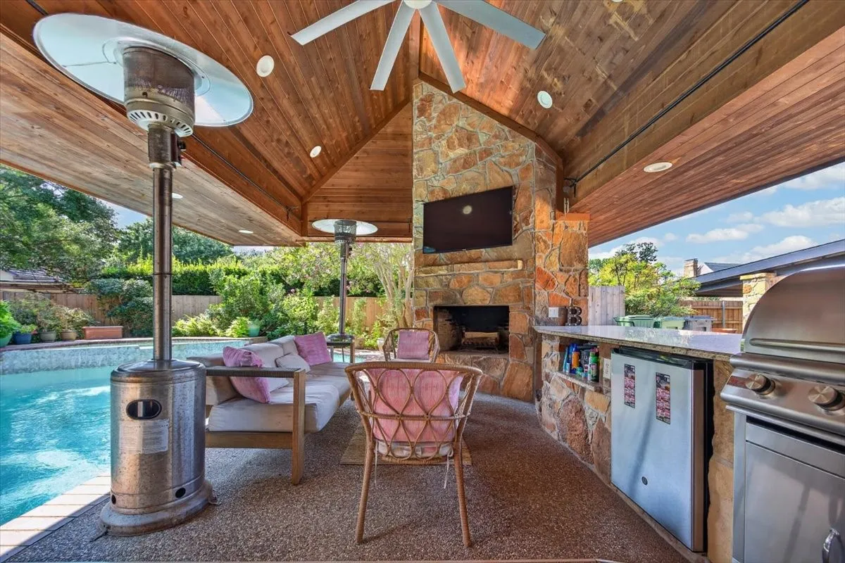 Welcome to the Outdoor Living Area. Granite countertops, built in Blaze gas grill, bar fridge, plenty of seating area, cantilevered roof over hanging the pool for shade, stone fireplace with gas starter, two Samsung TVs to watch all the games, high volume fan.