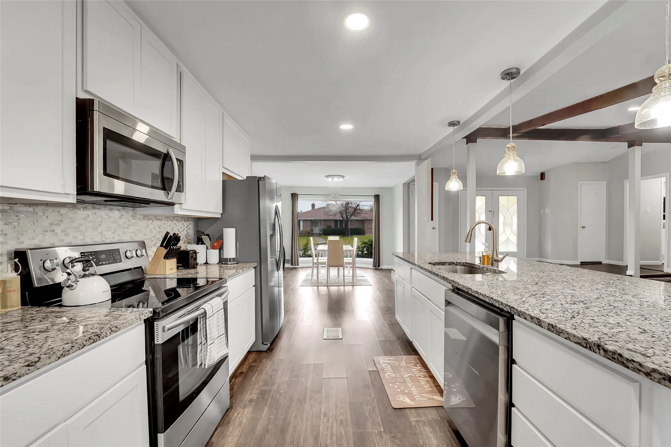 Kitchen featuring white cabinetry, granite countertops, stainless steel appliances, wood-finish flooring, and recessed lighting
