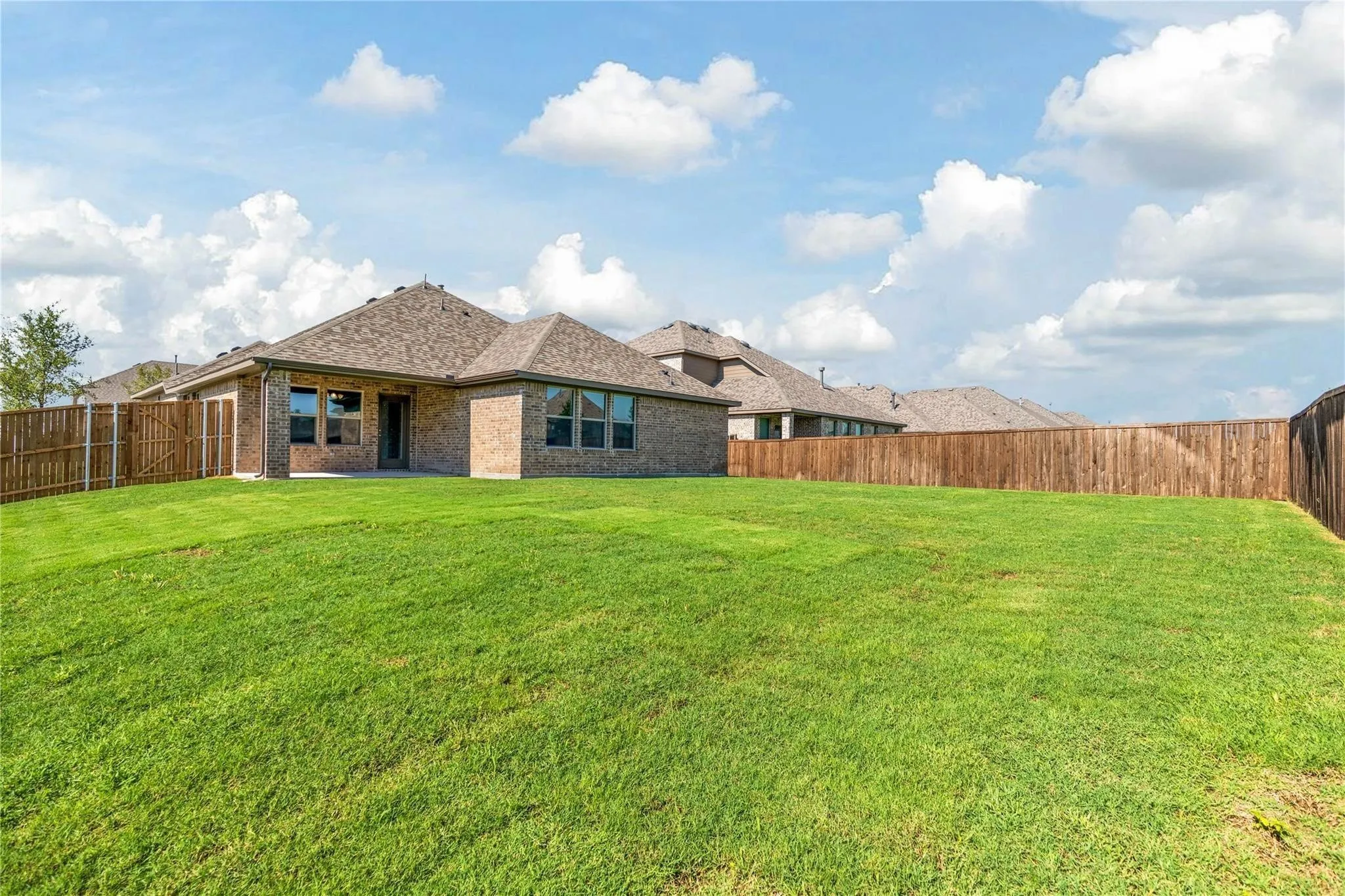 Expansive green lawn with a full privacy fence