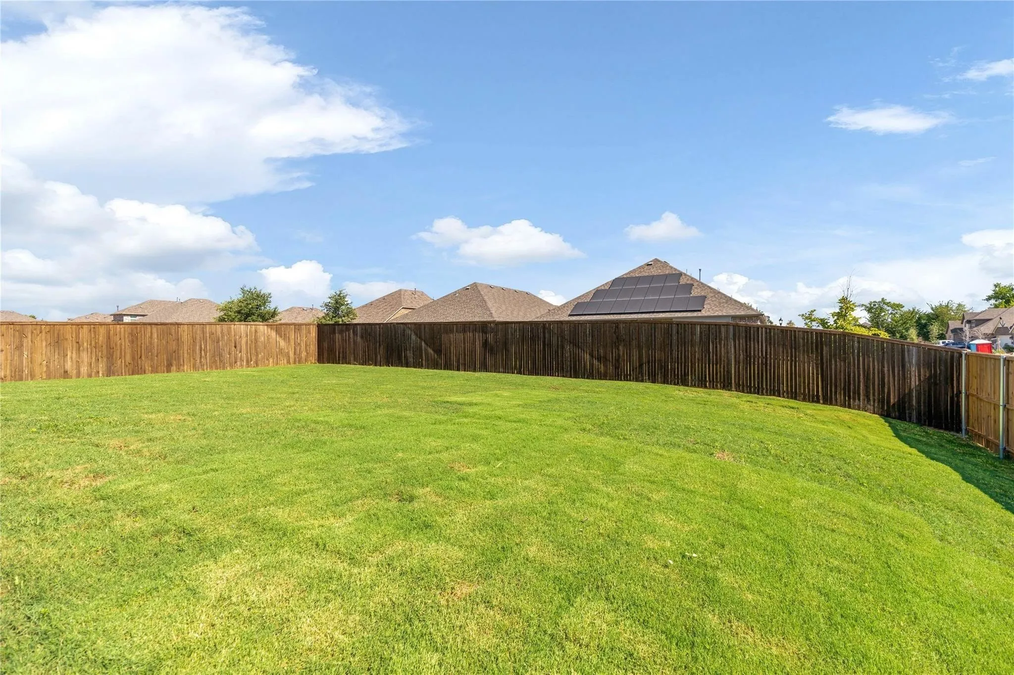 Expansive grassy yard with a wood privacy fence