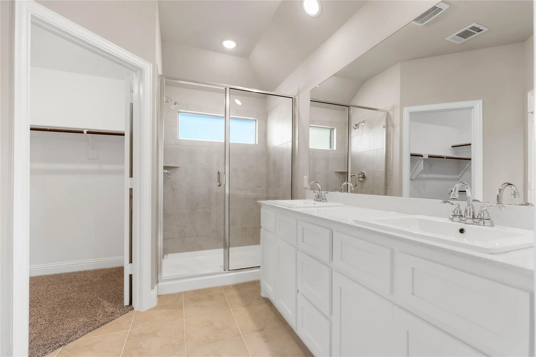 Dual vanity with white cabinetry and integrated sinks, glass-enclosed shower with tile surround, built-in shelving in closet