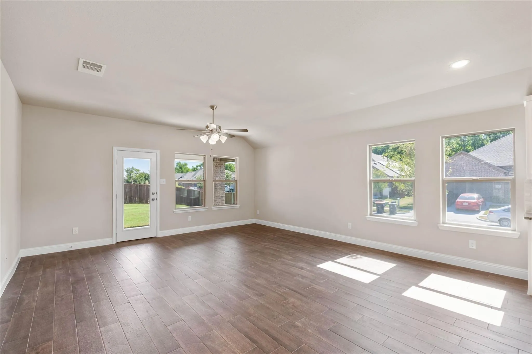 Vaulted ceiling with a ceiling fan and recessed lighting, wood-finish flooring, and multiple windows