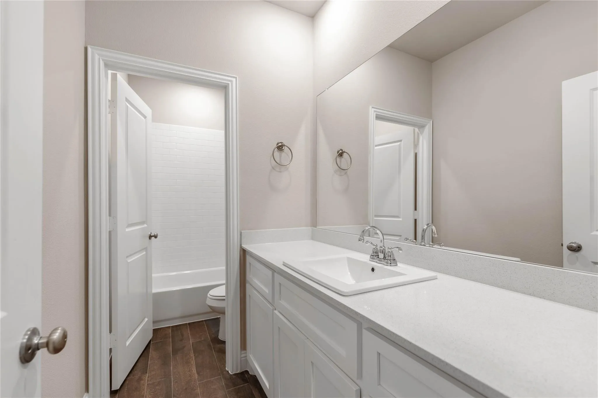 Bathroom featuring a built-in vanity with a single sink, white cabinetry, a light-toned countertop, and wood-finish flooring