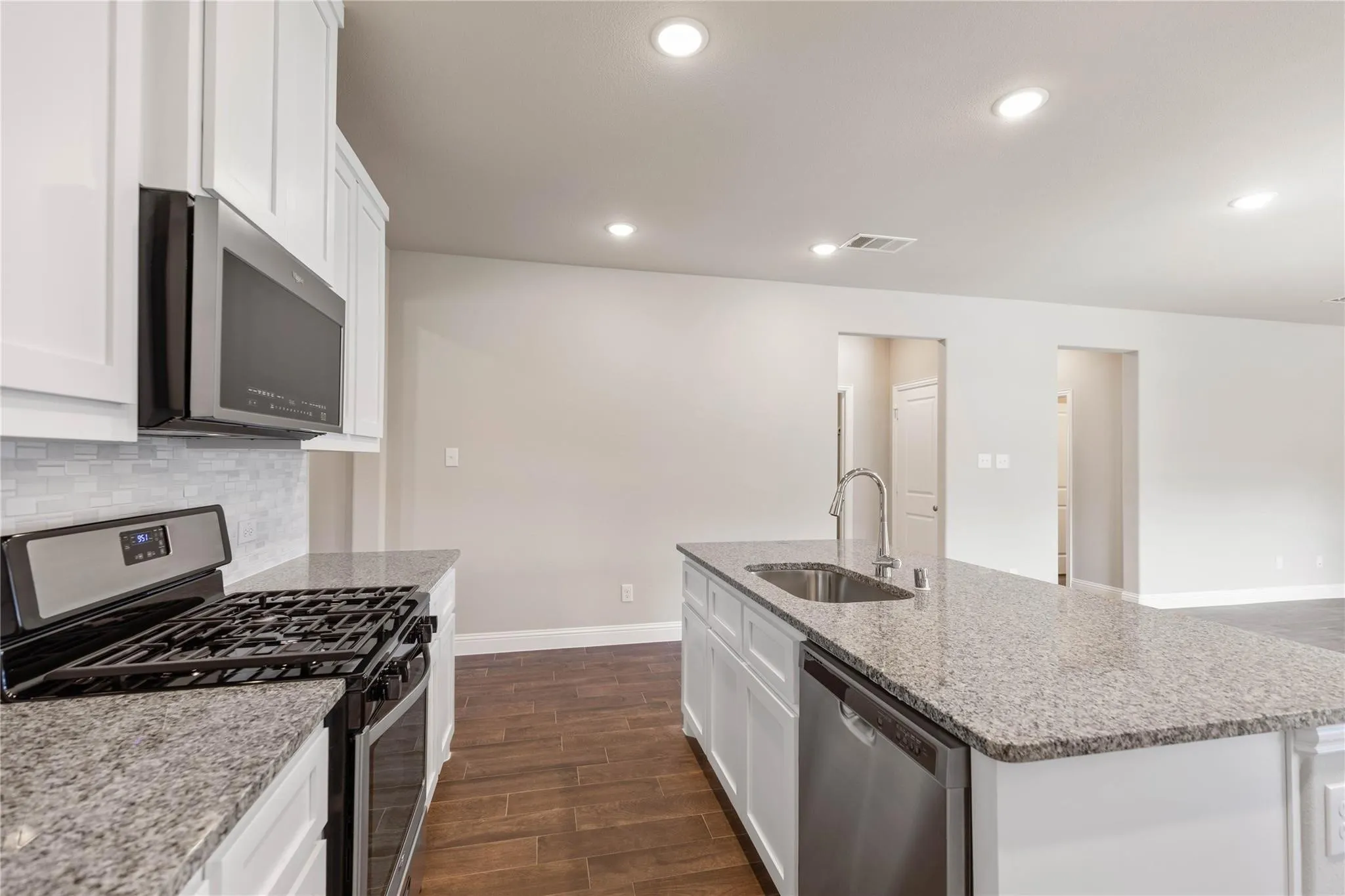 Kitchen featuring wood-finish flooring, white cabinetry, granite countertops, and recessed lighting