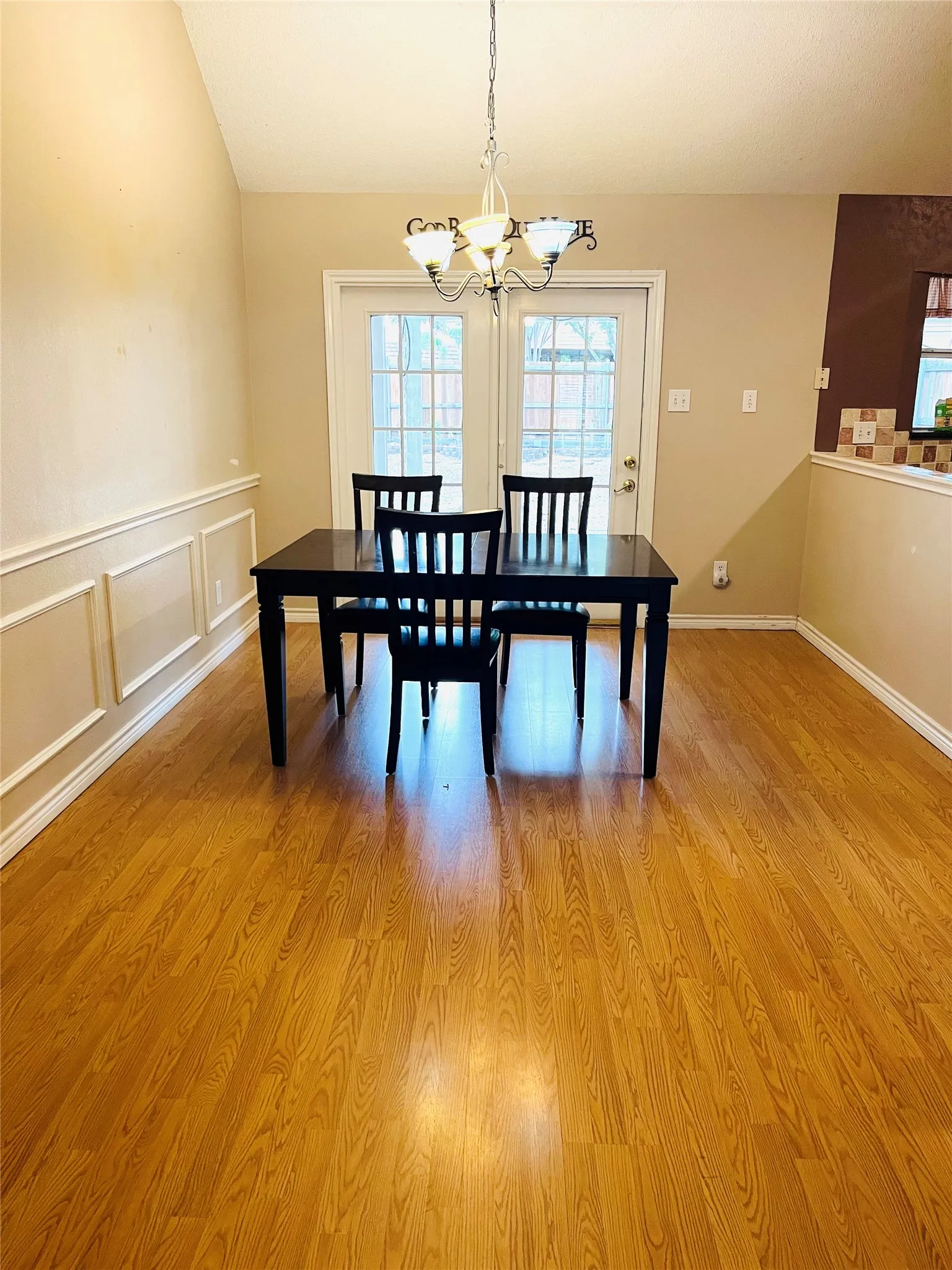 Vaulted ceiling, wood-finish flooring, wainscoting, and French patio doors