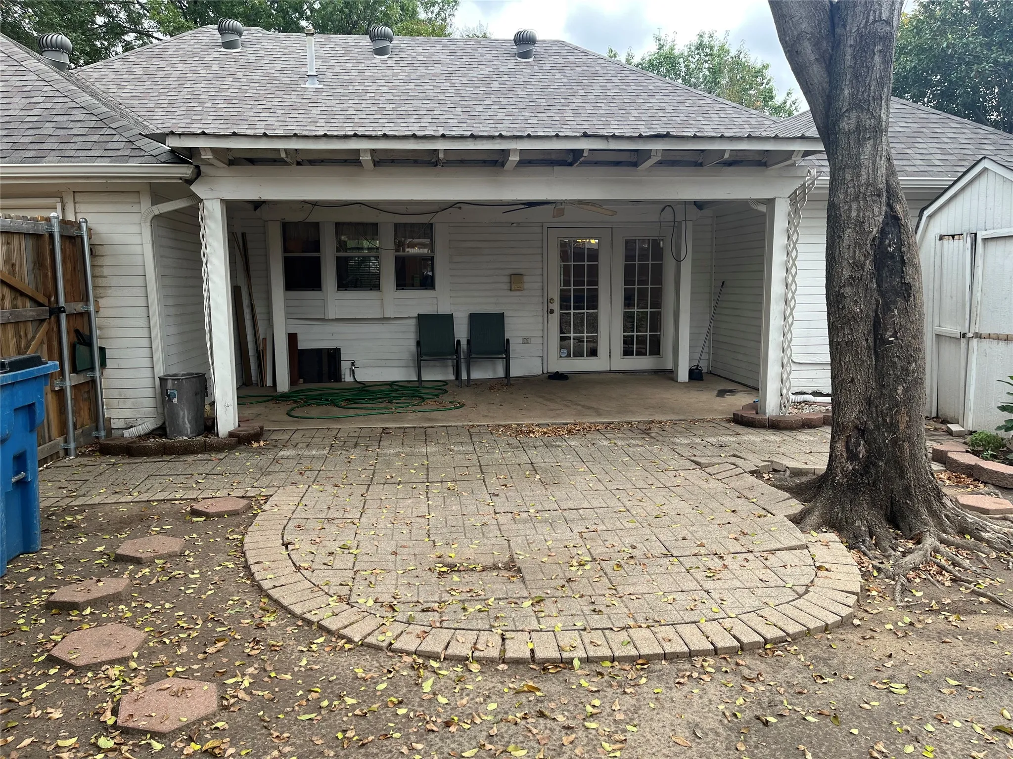 Covered patio with brick paver flooring, double glass panel doors, and shingled roof