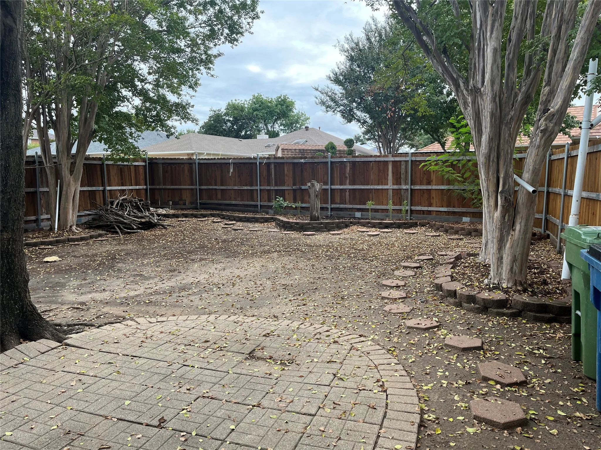 Expansive backyard featuring a wood privacy fence, established trees, a paver patio, and stepping stones