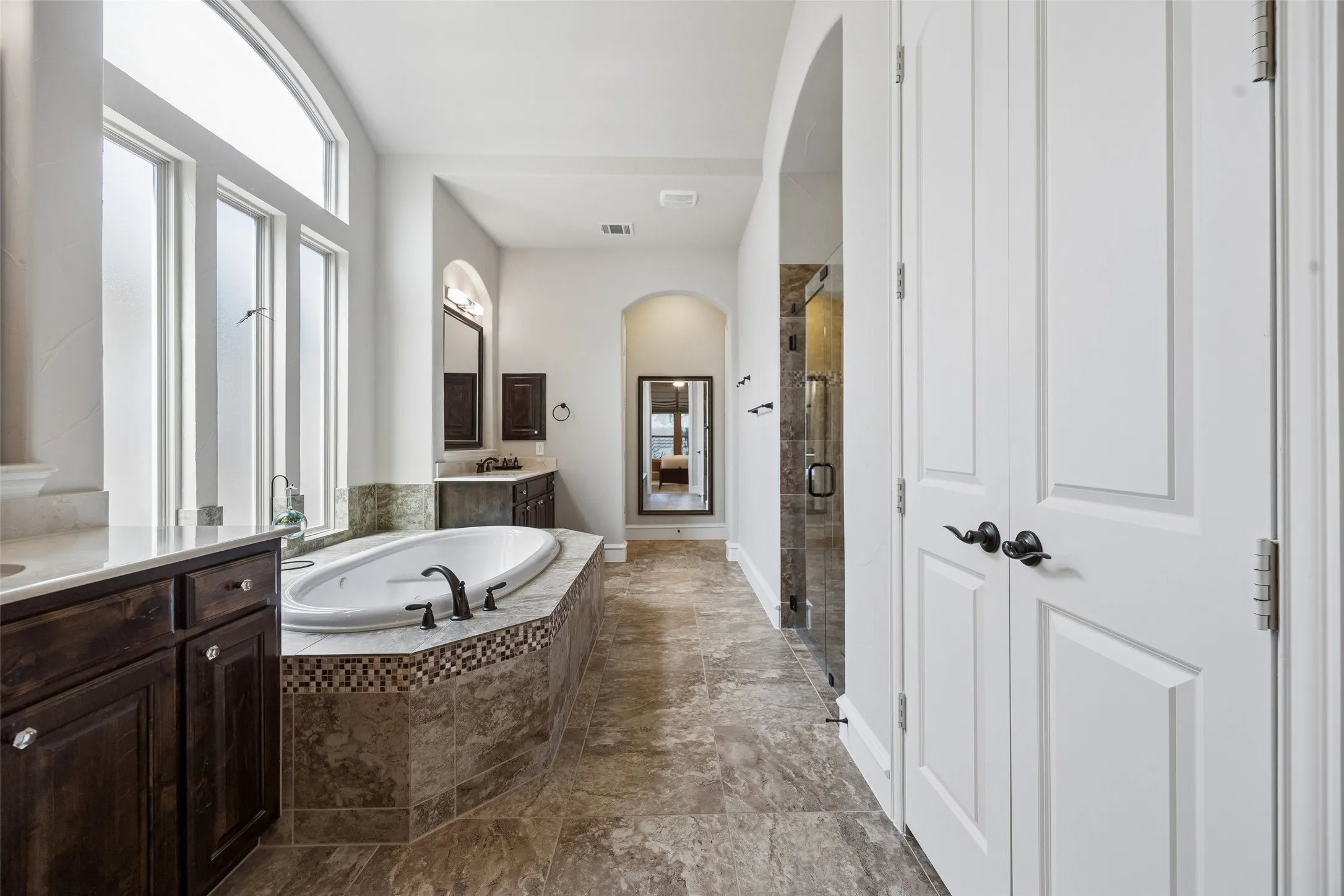 Primary bath with linen closet, built ins, jetted soaking tub, large walk in shower and a massive walk in closet.