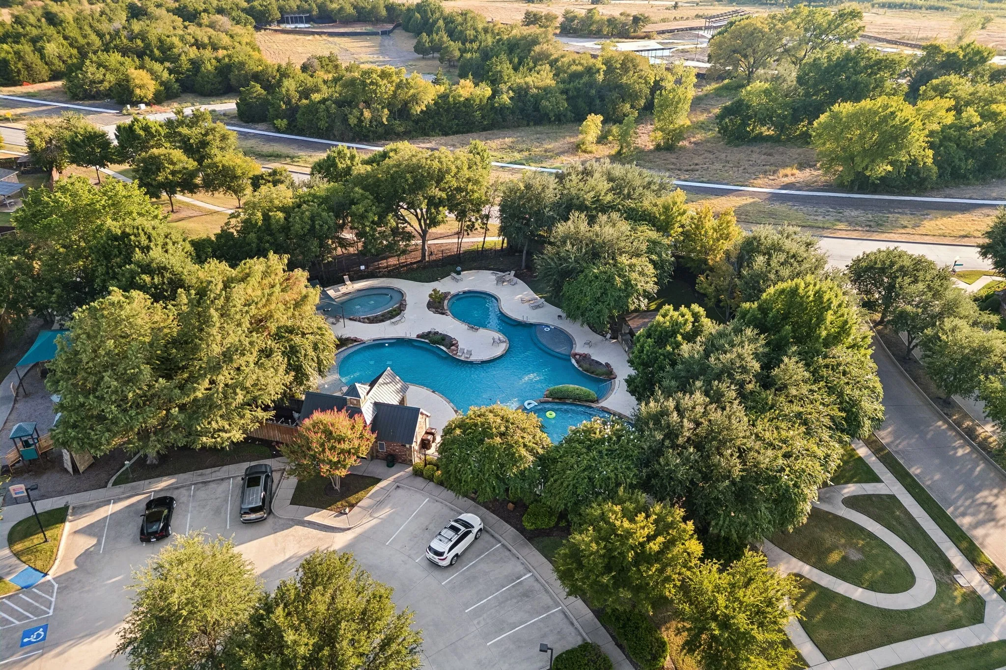 Resort-style pool with multiple swimming areas, integrated spa, and surrounding hardscaping