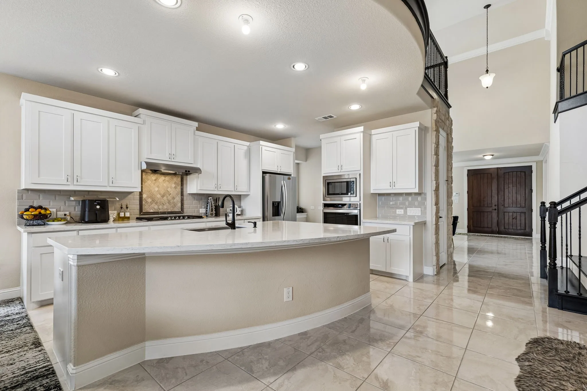 Kitchen featuring white cabinetry, a large kitchen island with a sink, stainless steel appliances, and a tiled backsplash