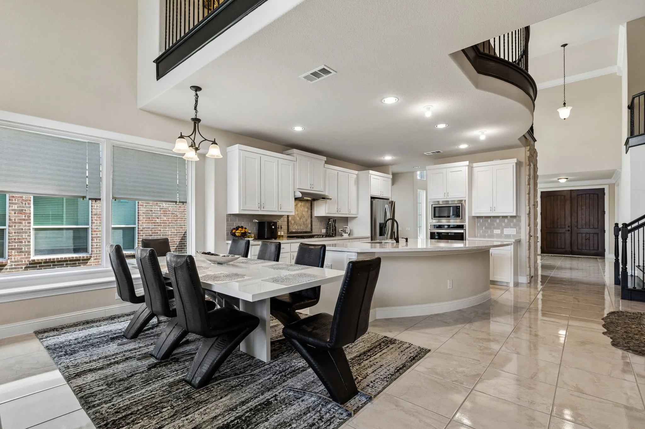 Two-story foyer with wood-finish double doors, tile flooring, and a chandelier