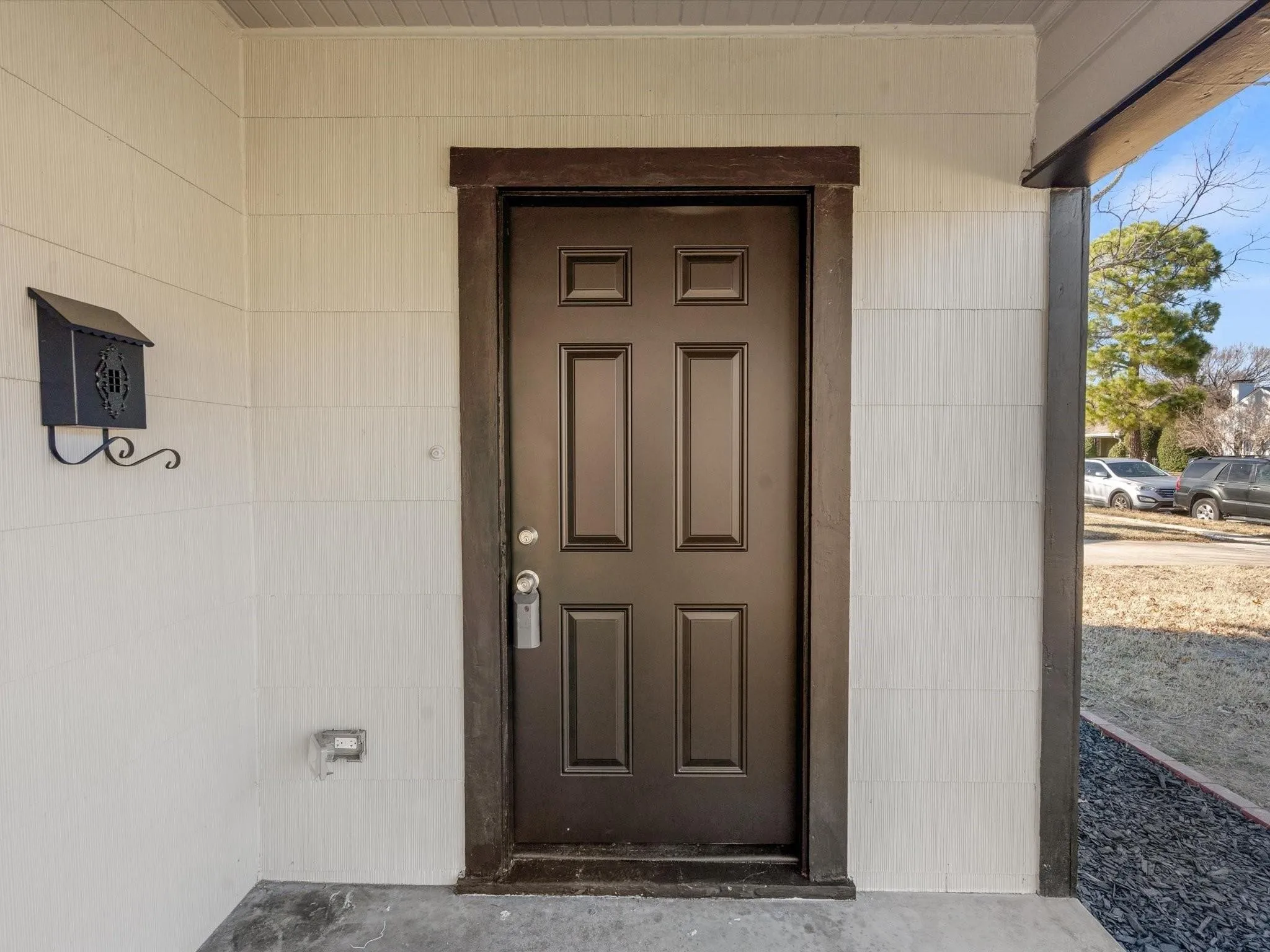 Panel exterior siding, dark paneled entry door, dark trim, and a decorative black mailbox