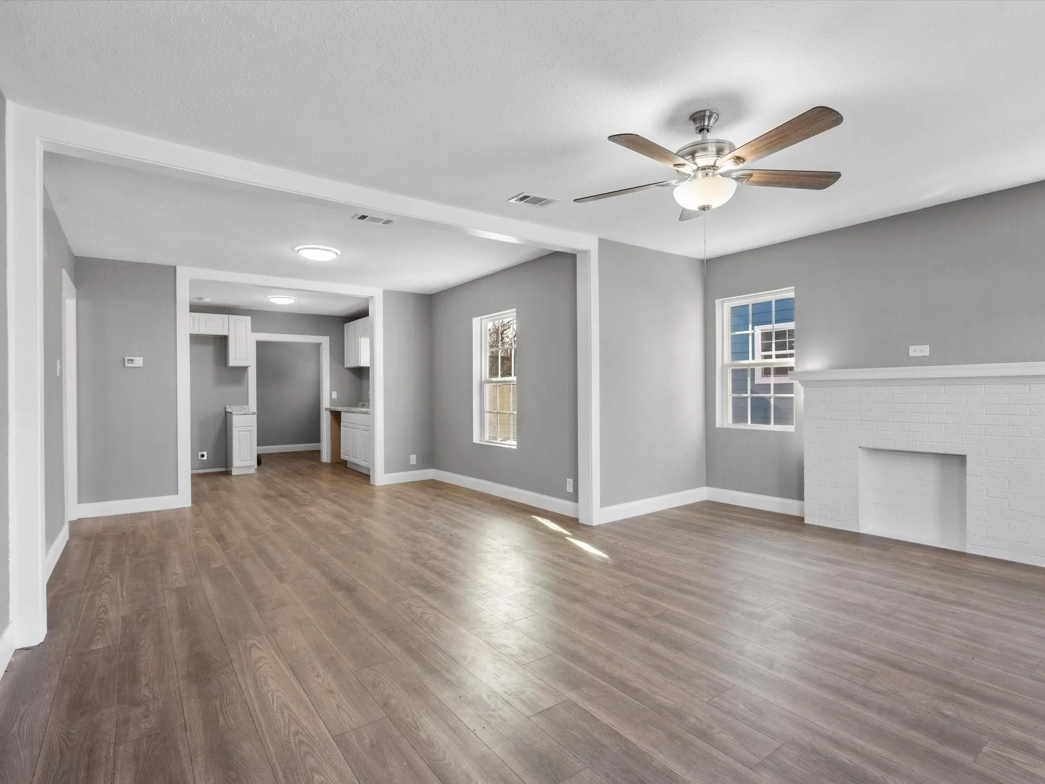 Wood-finish flooring throughout, complemented by a white brick fireplace