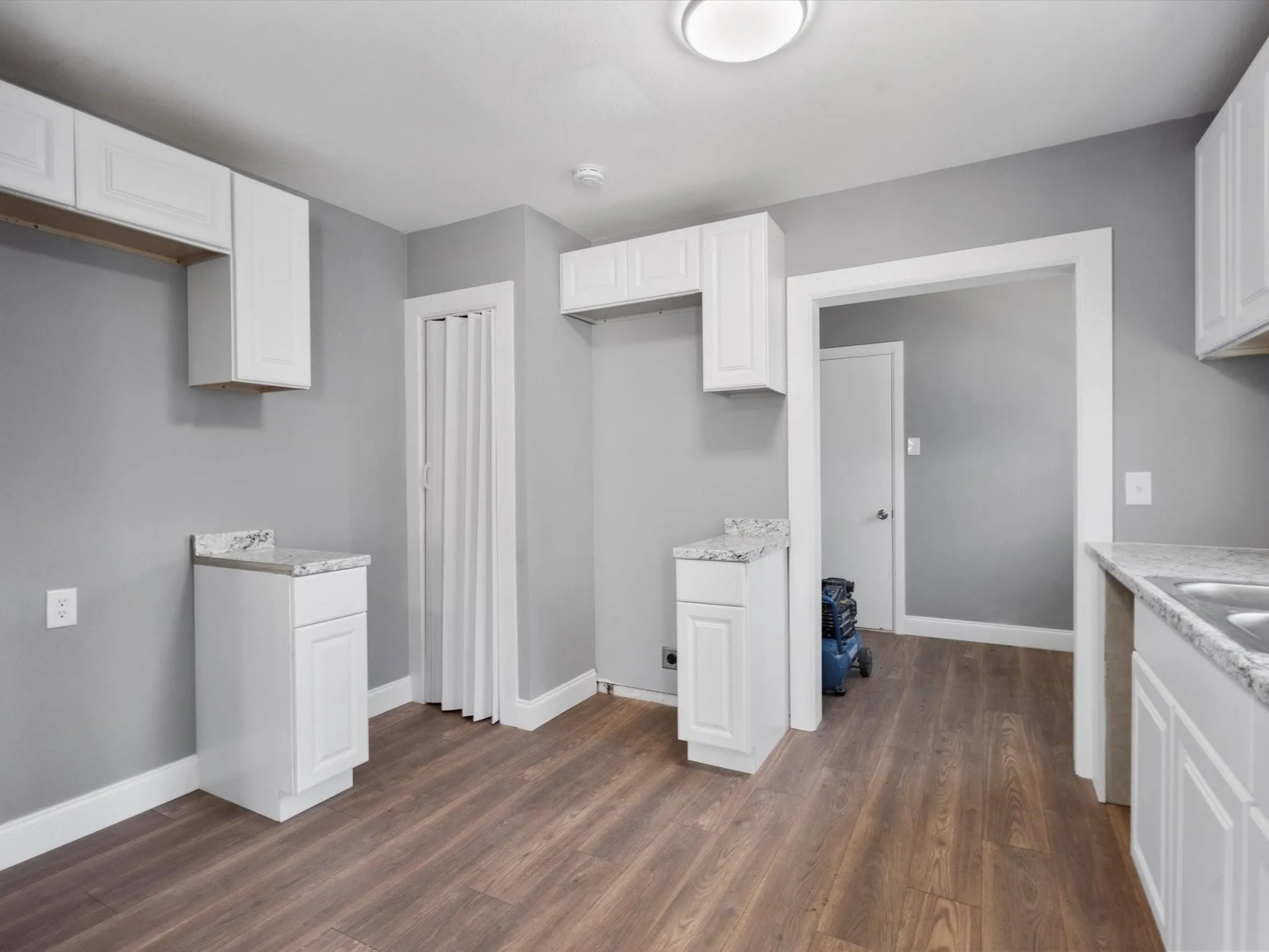 Wood-finish flooring, white cabinetry, light-toned countertops, and recessed ceiling lighting